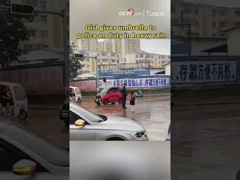 Girl gives umbrella to police on duty in heavy rain